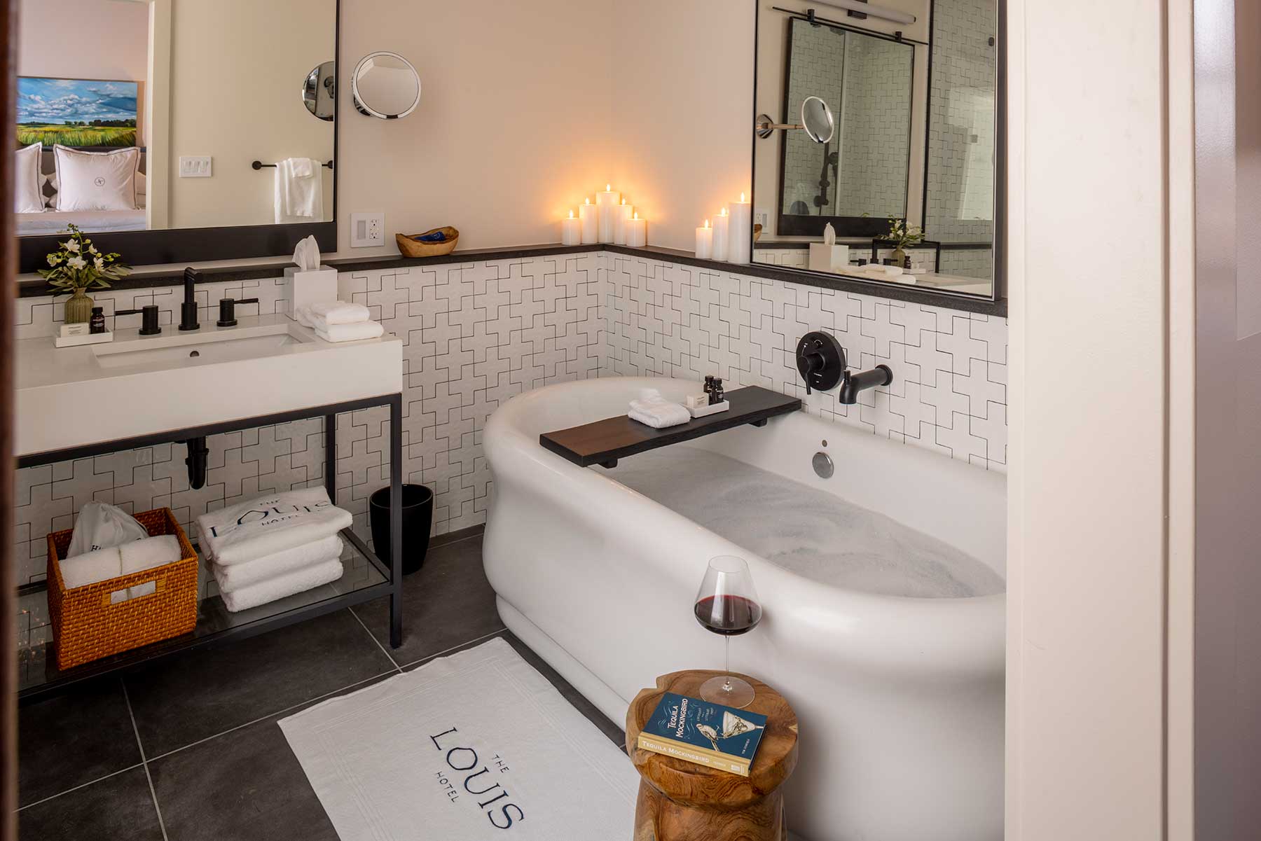 Photo of a guest bathroom at The Louis Hotel with a drawn bubble bath and glass of wine next to the tub.